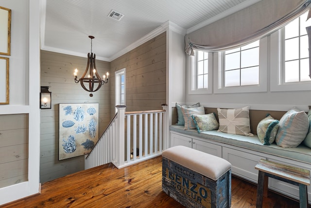 living area with crown molding, visible vents, an upstairs landing, dark wood-style floors, and an inviting chandelier