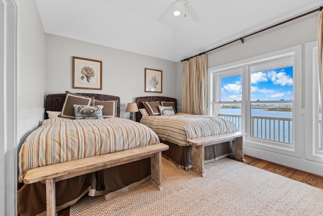 bedroom featuring a water view, light wood-style flooring, ceiling fan, and lofted ceiling