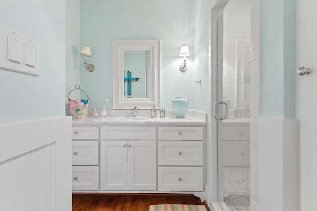 bathroom with wood finished floors, a shower stall, and vanity