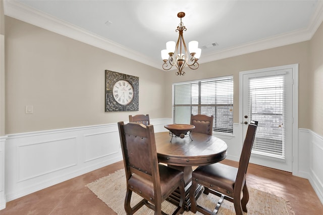 dining space with an inviting chandelier, ornamental molding, and a wainscoted wall