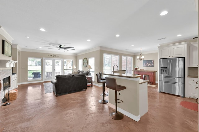 kitchen with a breakfast bar area, concrete floors, a fireplace, ornamental molding, and stainless steel fridge with ice dispenser