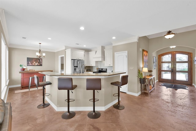 kitchen with arched walkways, stainless steel appliances, white cabinets, french doors, and custom range hood