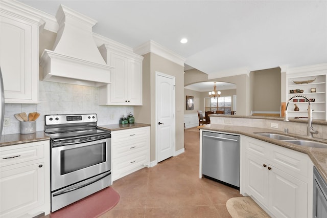 kitchen with arched walkways, an inviting chandelier, appliances with stainless steel finishes, a sink, and premium range hood