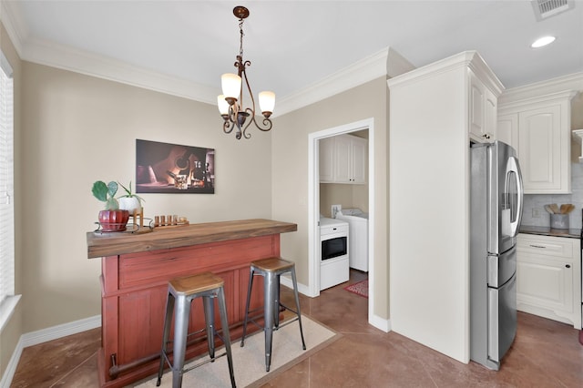 interior space with crown molding, washer and clothes dryer, decorative backsplash, stainless steel fridge, and baseboards