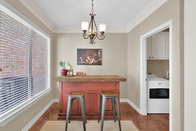 tiled dining space featuring baseboards, crown molding, washer / clothes dryer, and a notable chandelier