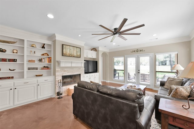 living room featuring recessed lighting, a fireplace, a ceiling fan, ornamental molding, and french doors