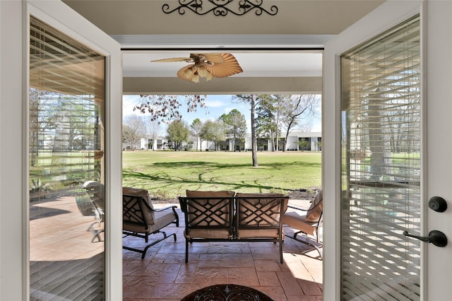 doorway with a healthy amount of sunlight, ceiling fan, and stone tile flooring