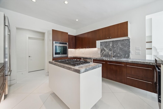 kitchen featuring light tile patterned floors, appliances with stainless steel finishes, a sink, and a center island