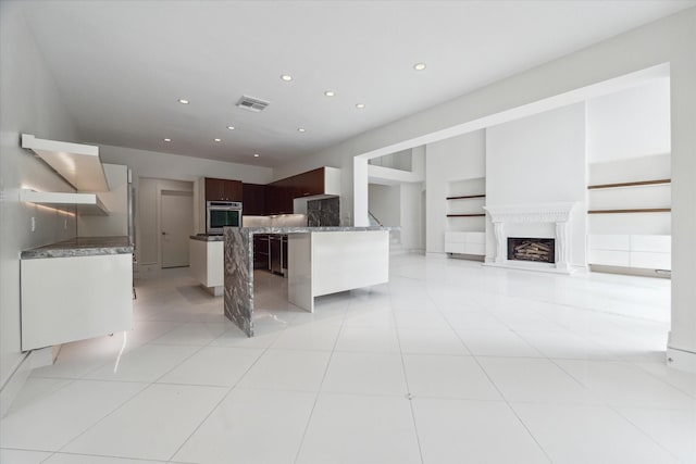 kitchen featuring oven, visible vents, open floor plan, dark brown cabinets, and modern cabinets