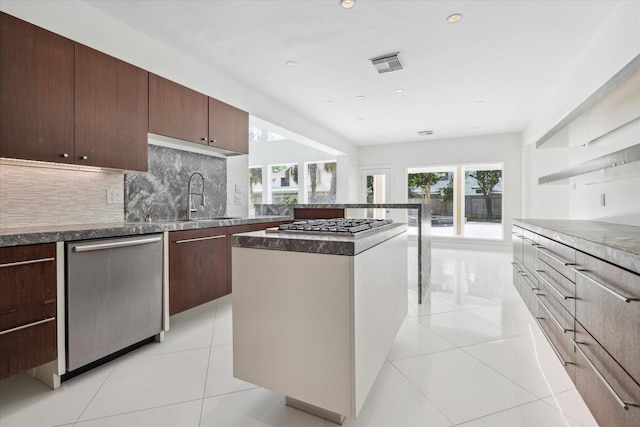 kitchen with appliances with stainless steel finishes, a center island, decorative backsplash, and light tile patterned floors