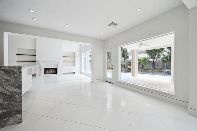 unfurnished living room with built in shelves, light tile patterned floors, recessed lighting, visible vents, and a fireplace with raised hearth