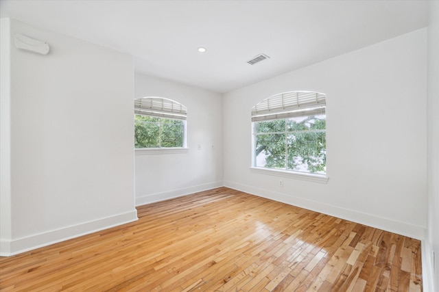 spare room featuring baseboards, visible vents, and light wood-style floors