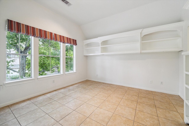 unfurnished room with lofted ceiling, light tile patterned floors, baseboards, and visible vents