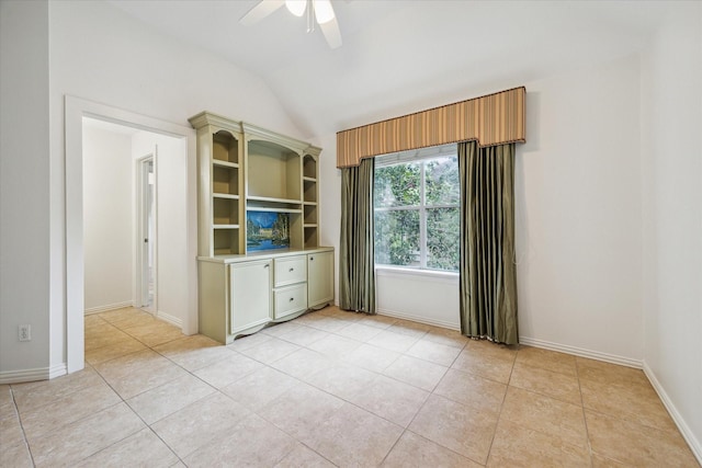 empty room featuring baseboards, vaulted ceiling, a ceiling fan, and light tile patterned flooring