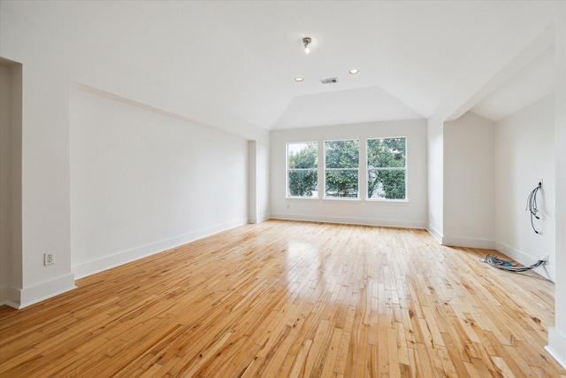 spare room with light wood finished floors, lofted ceiling, recessed lighting, visible vents, and baseboards