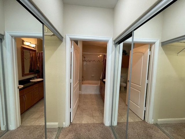 hall featuring light tile patterned floors, a sink, and light colored carpet