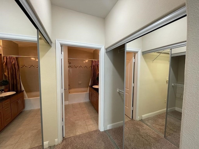 bathroom with tile patterned flooring, a spacious closet, and vanity