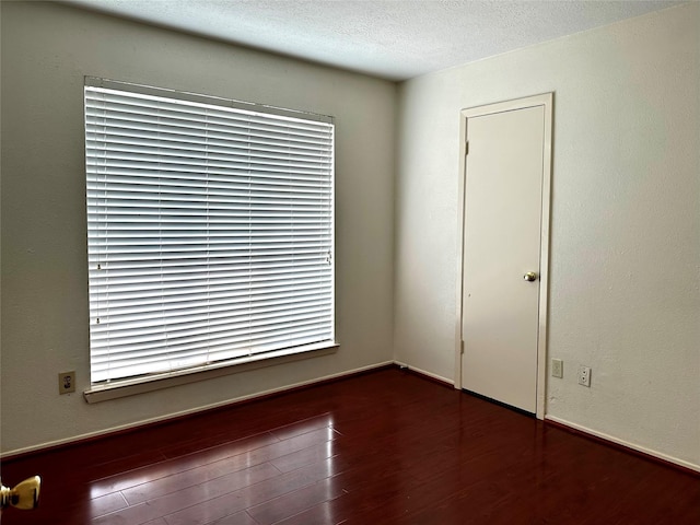 empty room with a textured ceiling and dark wood-type flooring