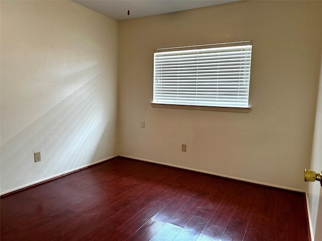 spare room with dark wood-type flooring and baseboards