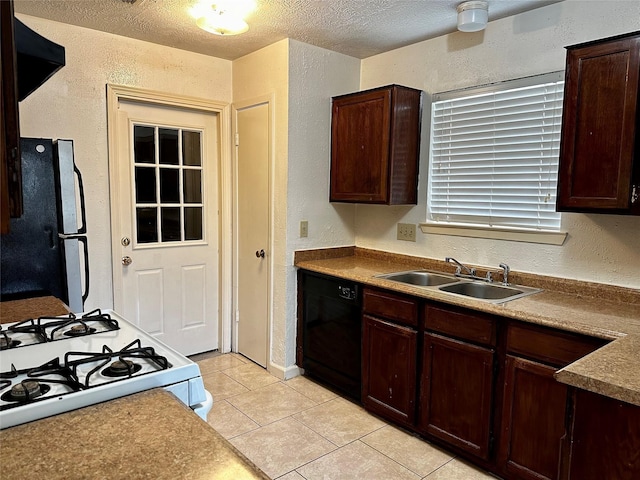 kitchen with black dishwasher, white range with gas cooktop, a textured wall, freestanding refrigerator, and a sink