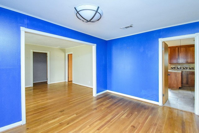 unfurnished room with light wood-style floors, baseboards, and visible vents