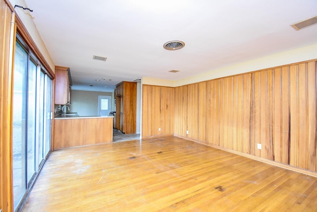 kitchen with light countertops, visible vents, light wood-style floors, a sink, and a peninsula