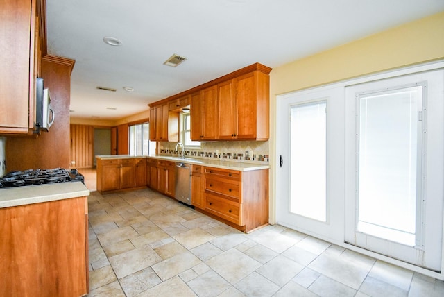 kitchen with brown cabinets, light countertops, dishwasher, and decorative backsplash