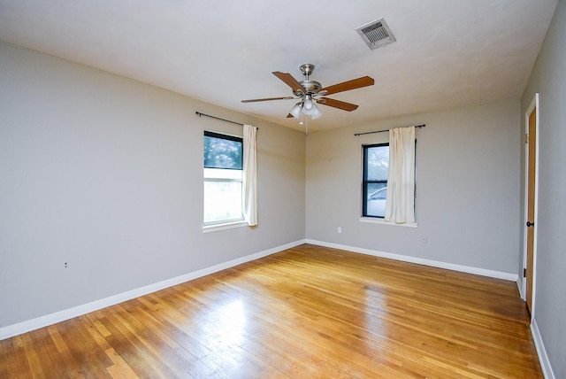 empty room with baseboards, visible vents, and light wood finished floors