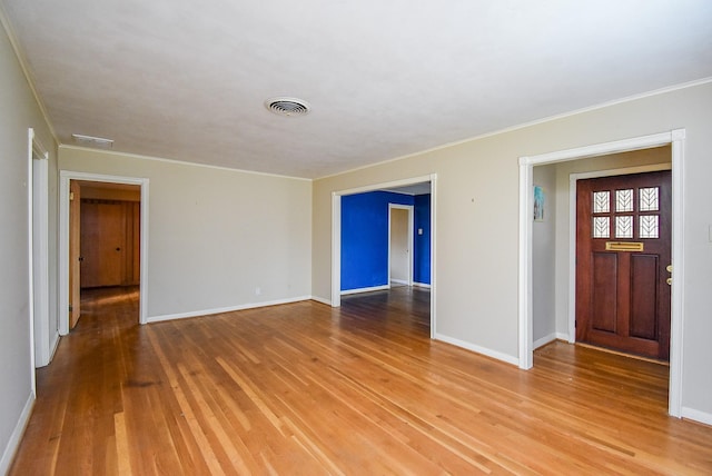 empty room featuring ornamental molding, baseboards, visible vents, and light wood finished floors