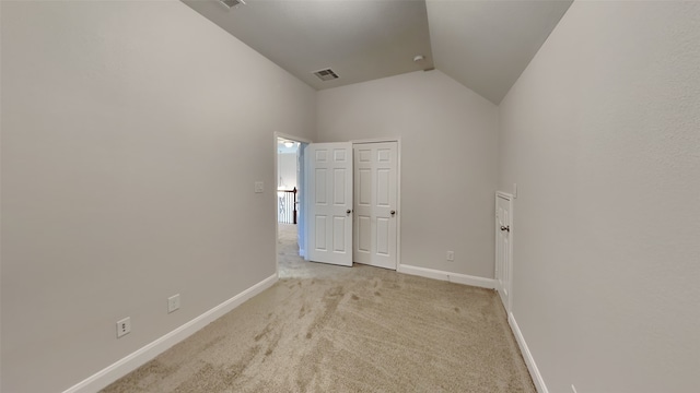 empty room with light carpet, lofted ceiling, visible vents, and baseboards