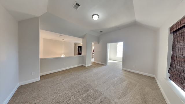 unfurnished room with carpet, arched walkways, visible vents, vaulted ceiling, and baseboards