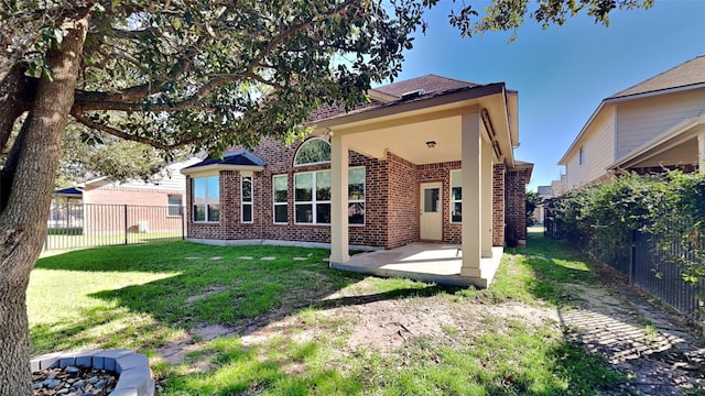 back of house featuring a yard, a fenced backyard, a patio, and brick siding