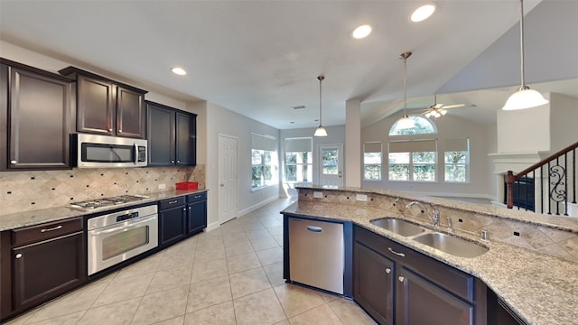 kitchen featuring appliances with stainless steel finishes, a sink, light stone counters, and tasteful backsplash