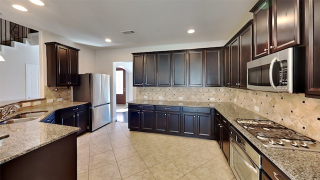 kitchen with light stone countertops, visible vents, stainless steel appliances, and a sink