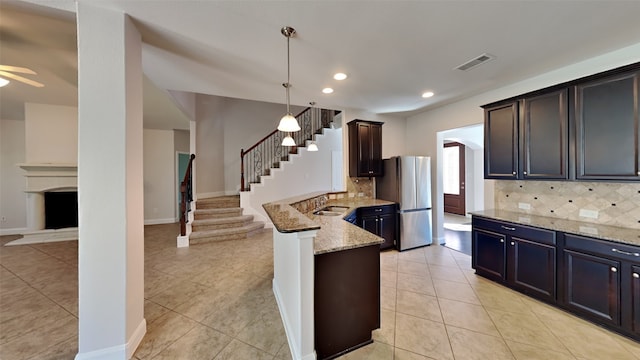 kitchen with light tile patterned floors, a sink, visible vents, freestanding refrigerator, and light stone countertops