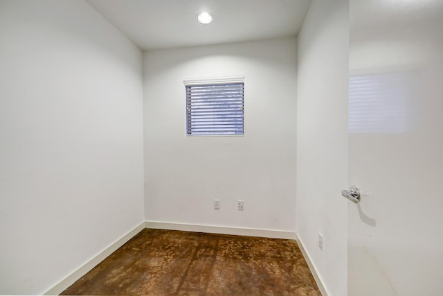 spare room with baseboards and unfinished concrete floors