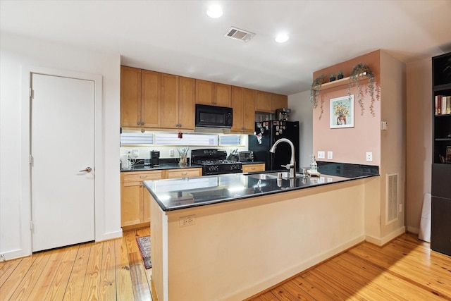 kitchen featuring a peninsula, black appliances, dark countertops, and visible vents