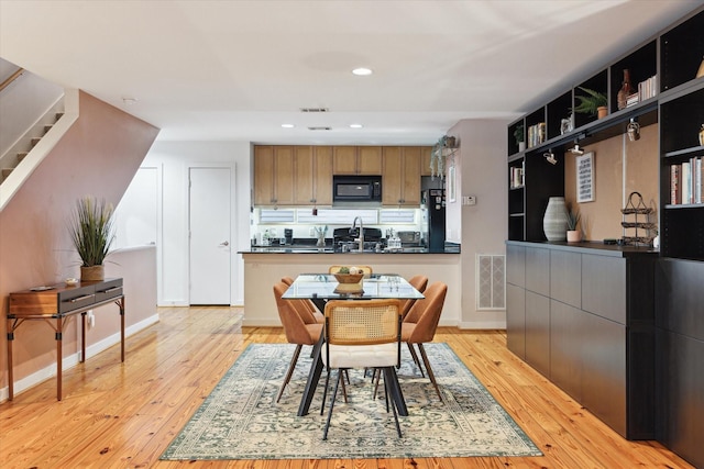 kitchen with dark countertops, light wood-style flooring, visible vents, and black microwave