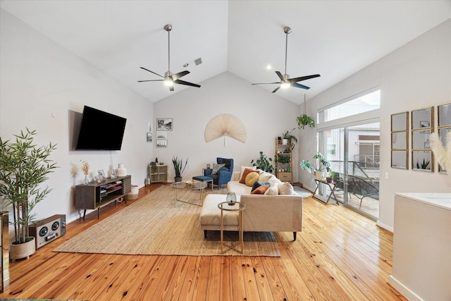 living area with light wood-style flooring, visible vents, high vaulted ceiling, and a ceiling fan