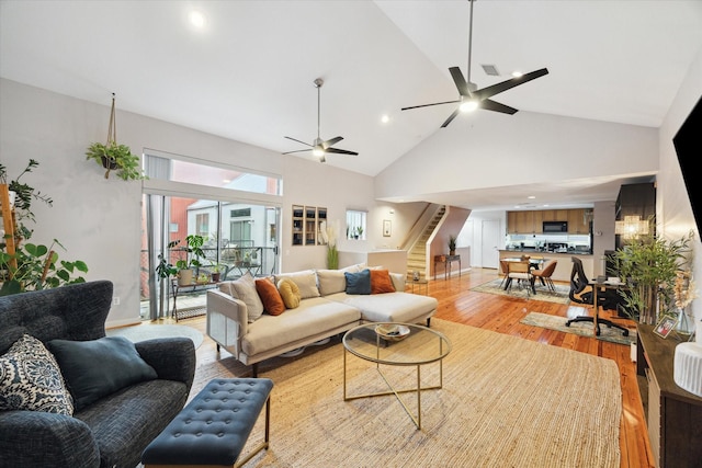 living room with visible vents, ceiling fan, stairway, light wood-style floors, and high vaulted ceiling