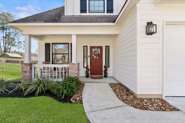 property entrance featuring a shingled roof, covered porch, and an attached garage