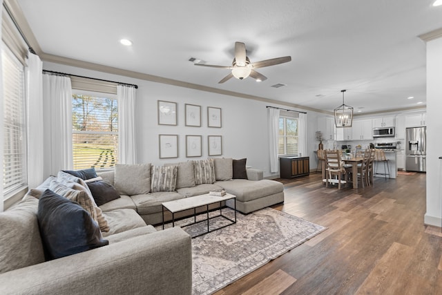 living area with ceiling fan with notable chandelier, dark wood-type flooring, and recessed lighting