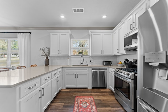 kitchen with visible vents, white cabinets, a peninsula, stainless steel appliances, and light countertops