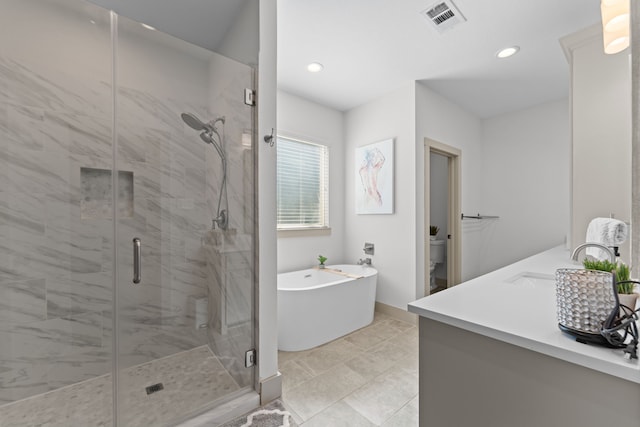 full bath featuring a stall shower, visible vents, toilet, a freestanding tub, and a sink