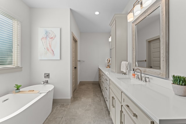 bathroom featuring recessed lighting, baseboards, a freestanding bath, and vanity