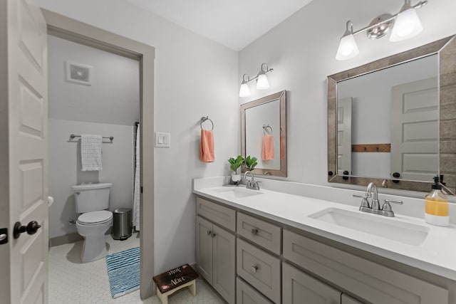 bathroom featuring toilet, double vanity, a sink, and visible vents