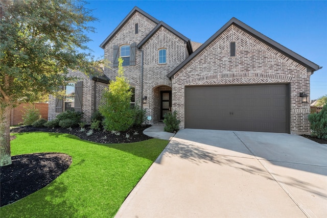 french country home featuring an attached garage, brick siding, fence, concrete driveway, and a front yard