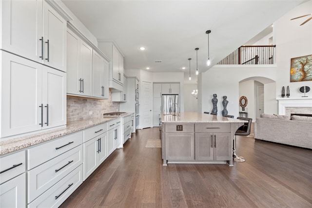 kitchen with a kitchen island, a breakfast bar area, open floor plan, hanging light fixtures, and white cabinetry