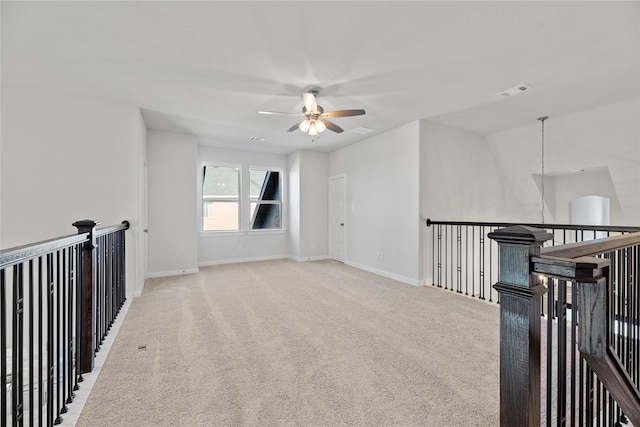 empty room with light carpet, a ceiling fan, visible vents, and baseboards