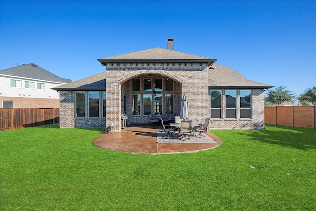 back of house with a patio, a fenced backyard, brick siding, a lawn, and roof with shingles